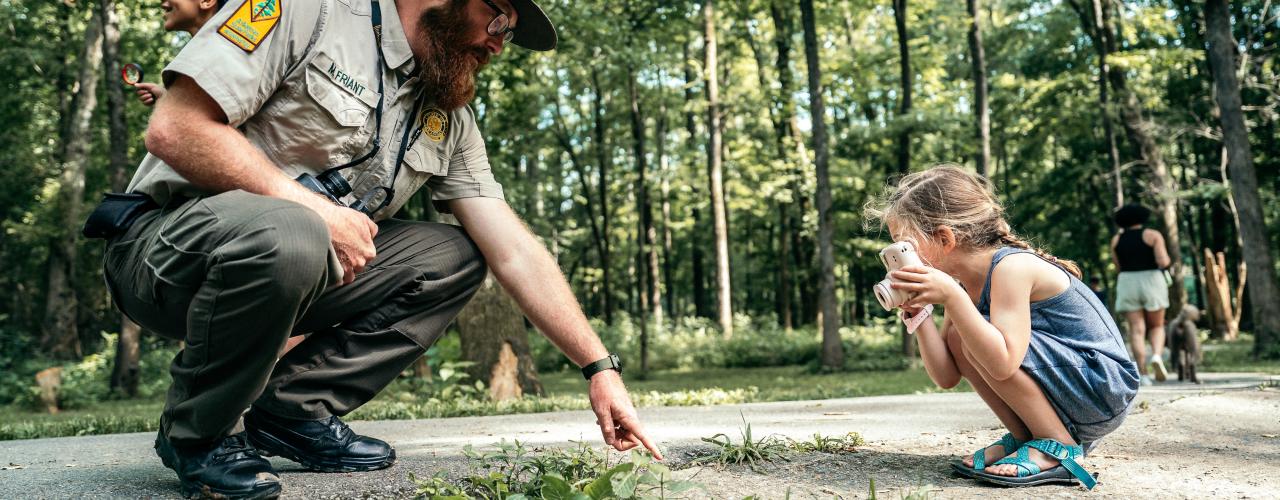 Park Ranger and kid looking at bugs and rocks